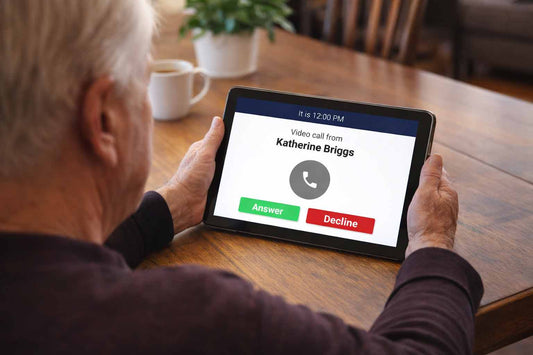 Older adult seated at a dining table viewing an incoming video call on a smart reminder clock