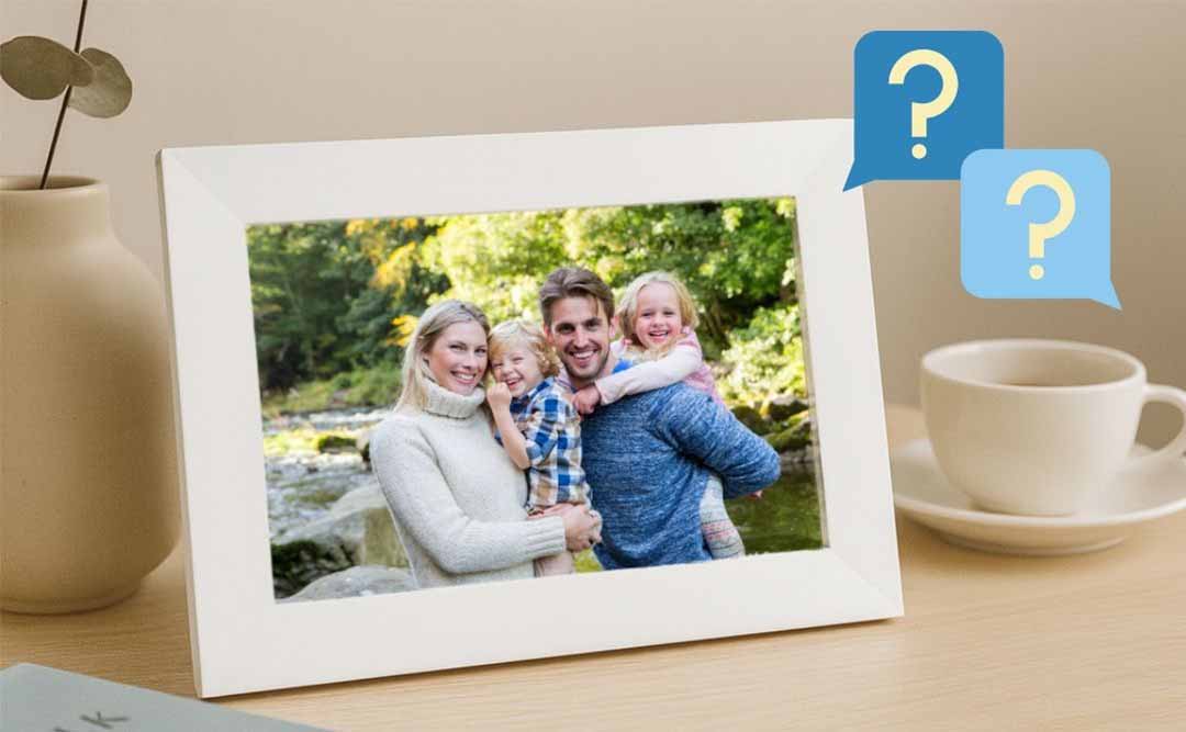 White digital photo frame displaying a family photo on a desk with question mark icons representing FAQs.