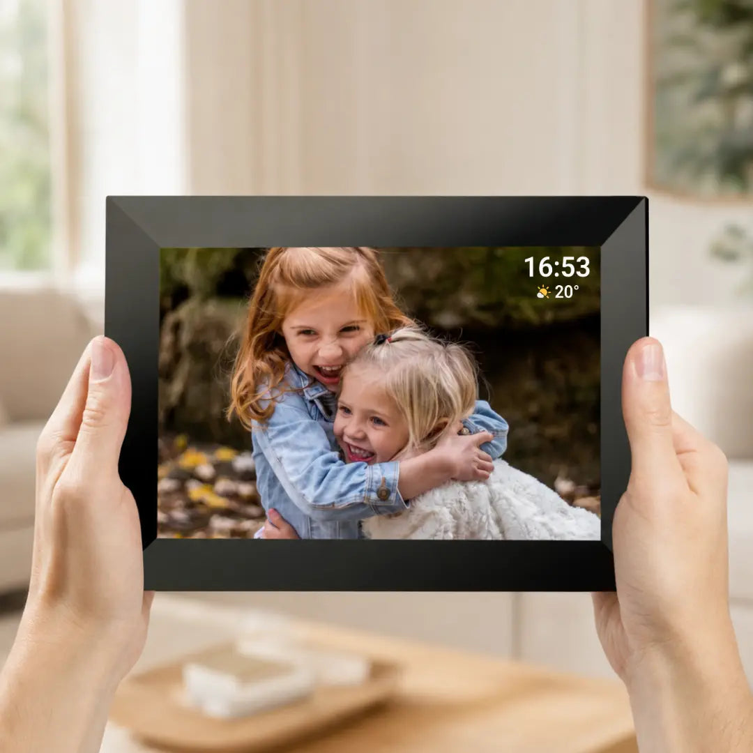 Hands holding a large-screen Lifeframe digital photo frame displaying a family photo, time and weather.