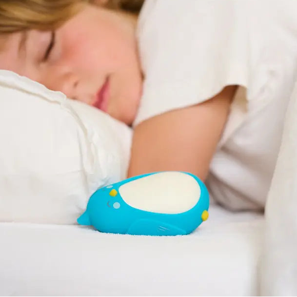Moonbuddy breathing coach for children resting beside a sleeping child at bedtime.