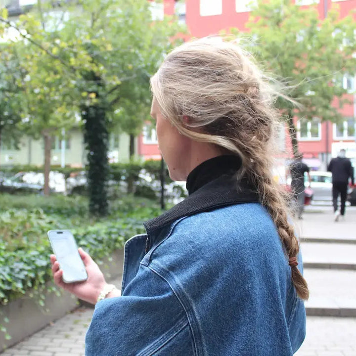 Woman using a mobile app outdoors to receive safety and care alerts from assistive technology.