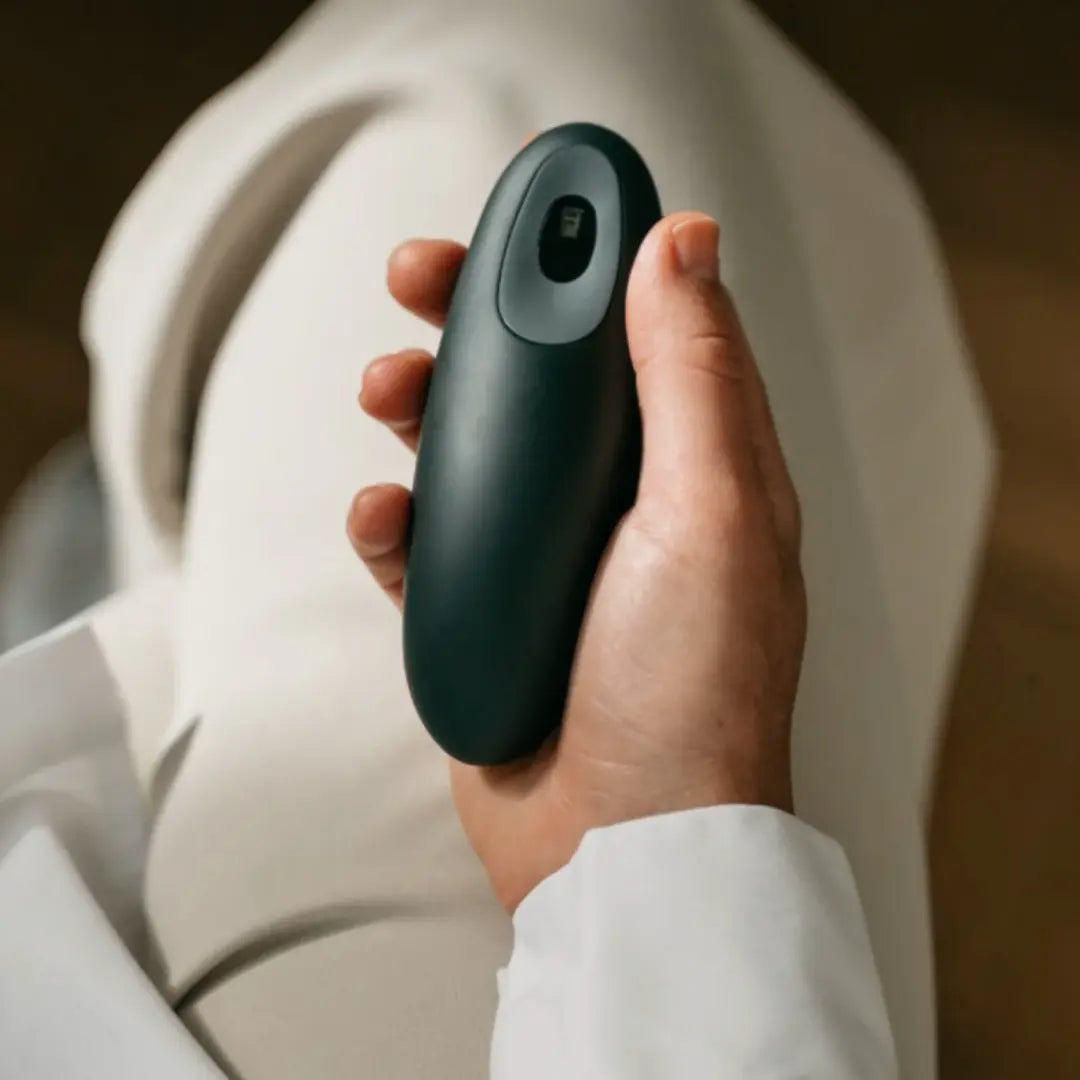 Person holding a dark green Moonbird breathing coach during a calming breathwork session.