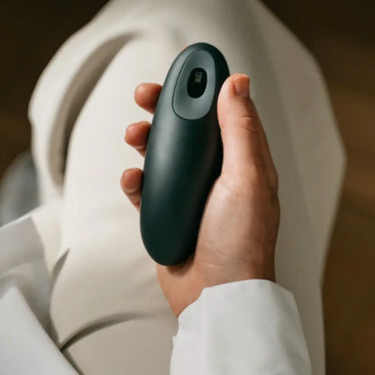 Person holding a dark green Moonbird breathing coach during a calming breathwork session.