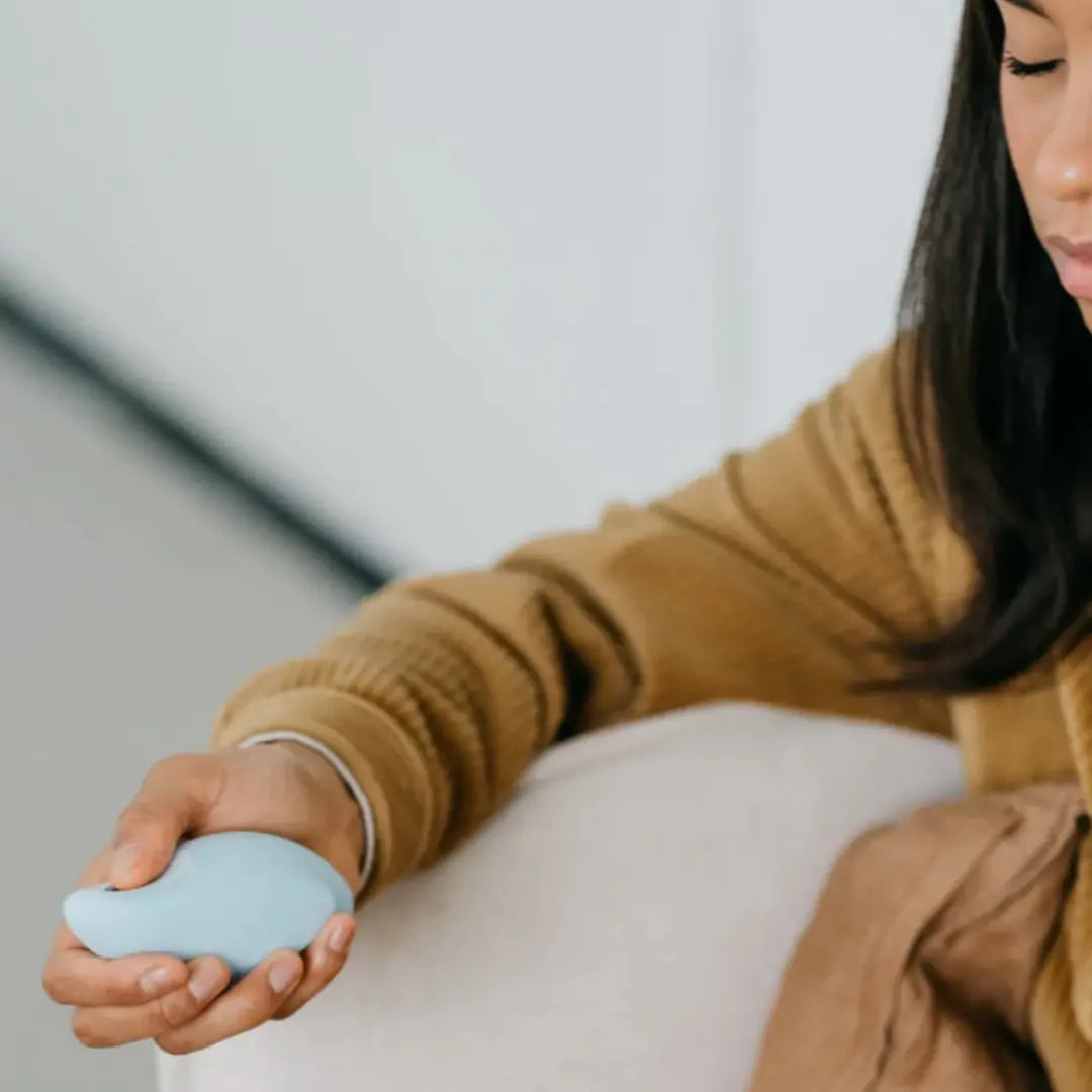 Woman holding a light blue Moonbird breathing coach for guided relaxation and stress relief.